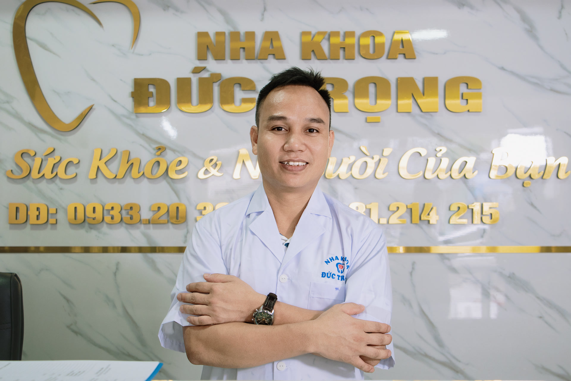 Bác sĩ đứng trước biển hiệu Nha khoa Đức Trọng tại quầy lễ tân