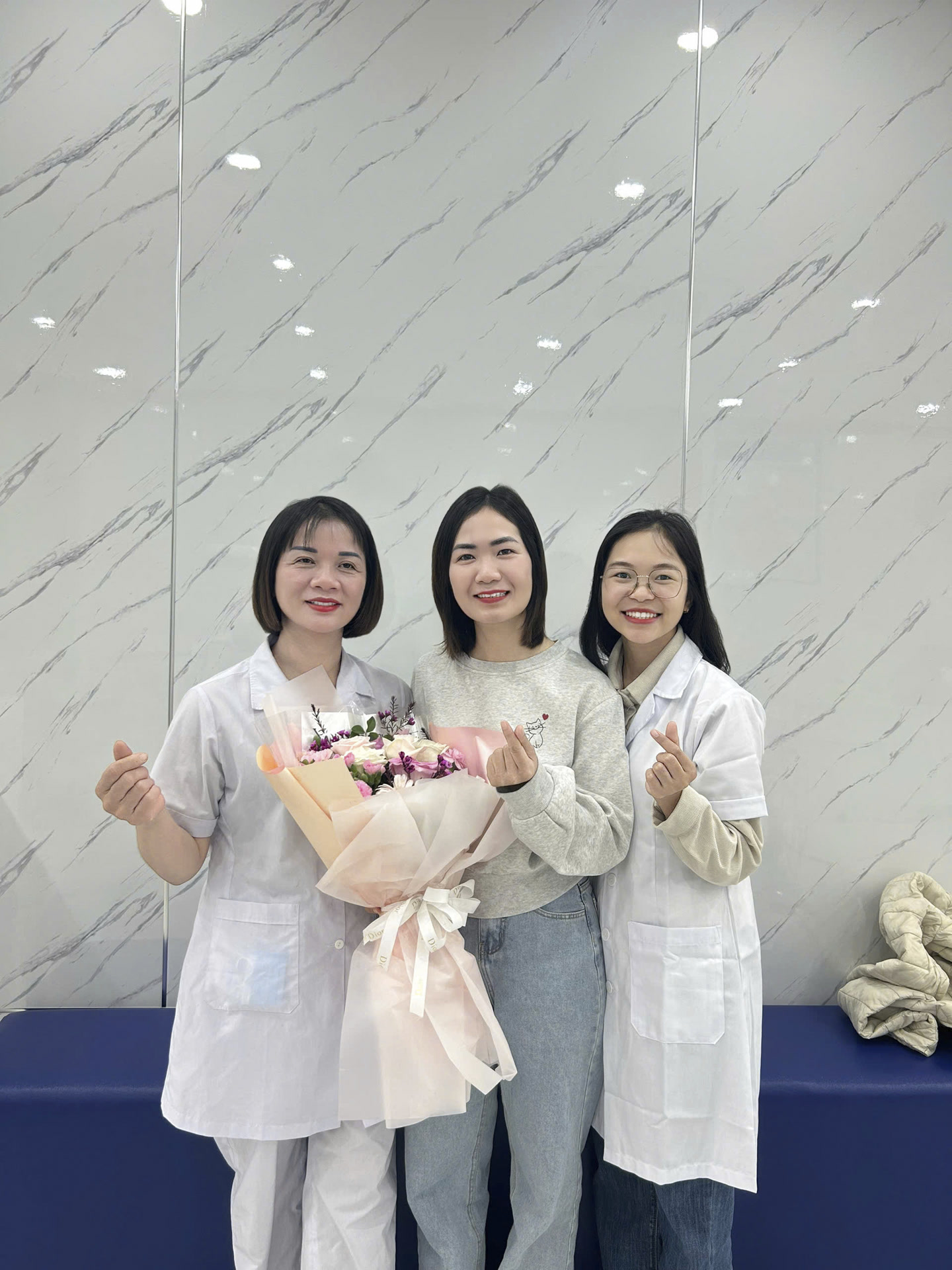 Nhân viên phòng khám chụp ảnh cùng một khách hàng sau khi điều trị xong